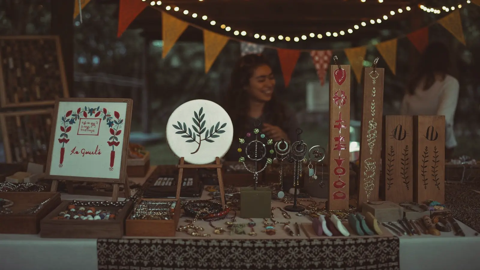 A craft marketplace booth displaying handmade jewelry, woven textiles, and cedar-themed art for sale at the festival