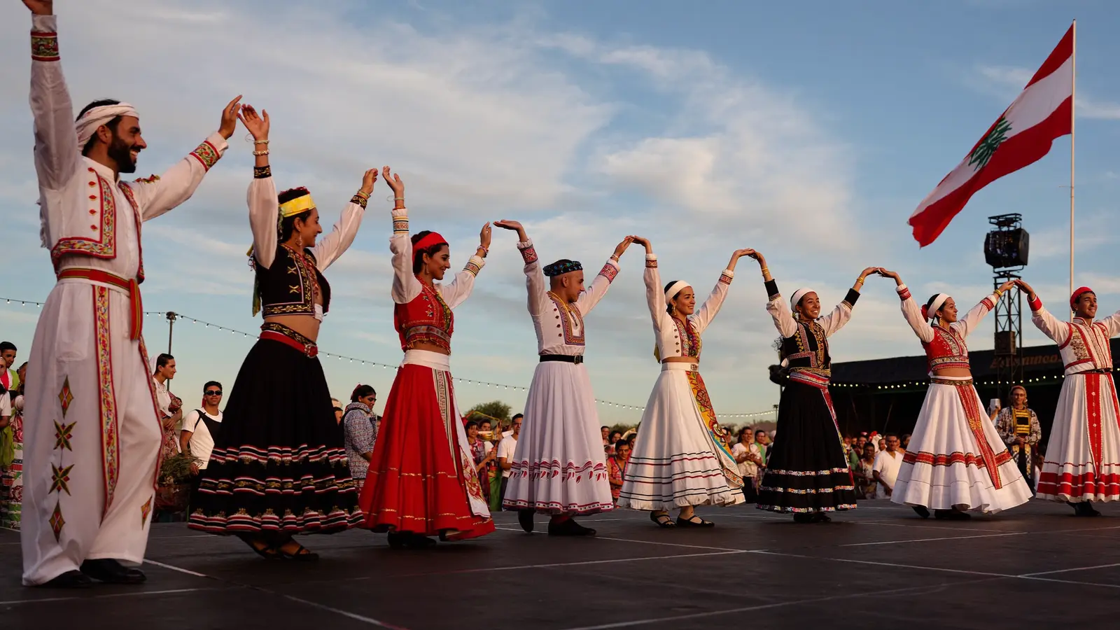 Dabke folk dancers in traditional embroidered dress performing a linked-arm line dance on stage at the festival