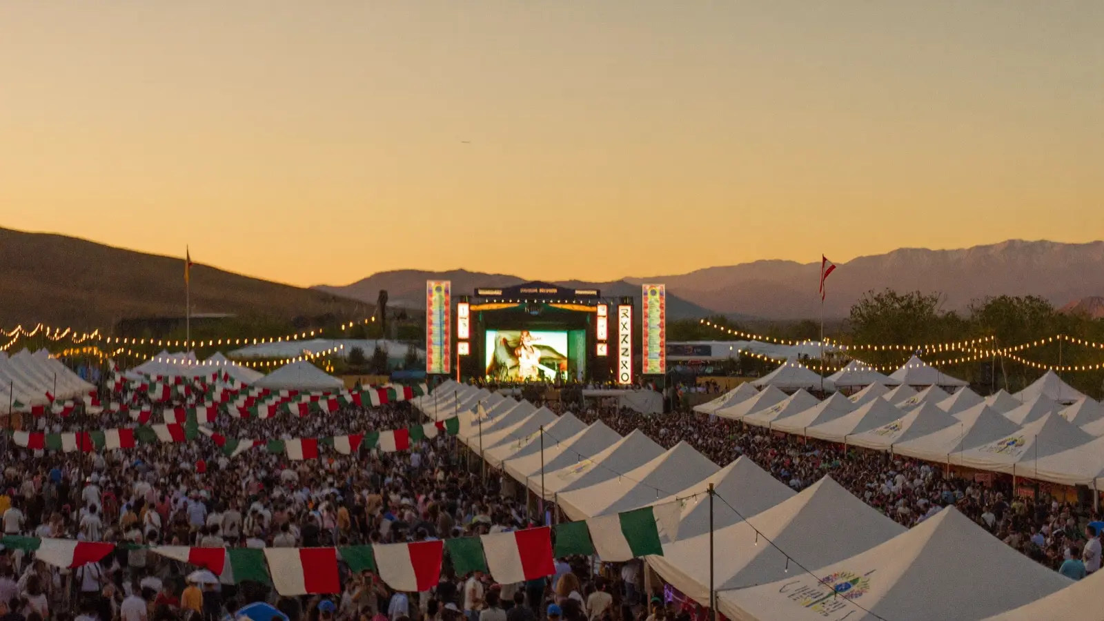 A large crowd of festival-goers gathered under glowing string lights at dusk across the festival grounds in Stockton, California